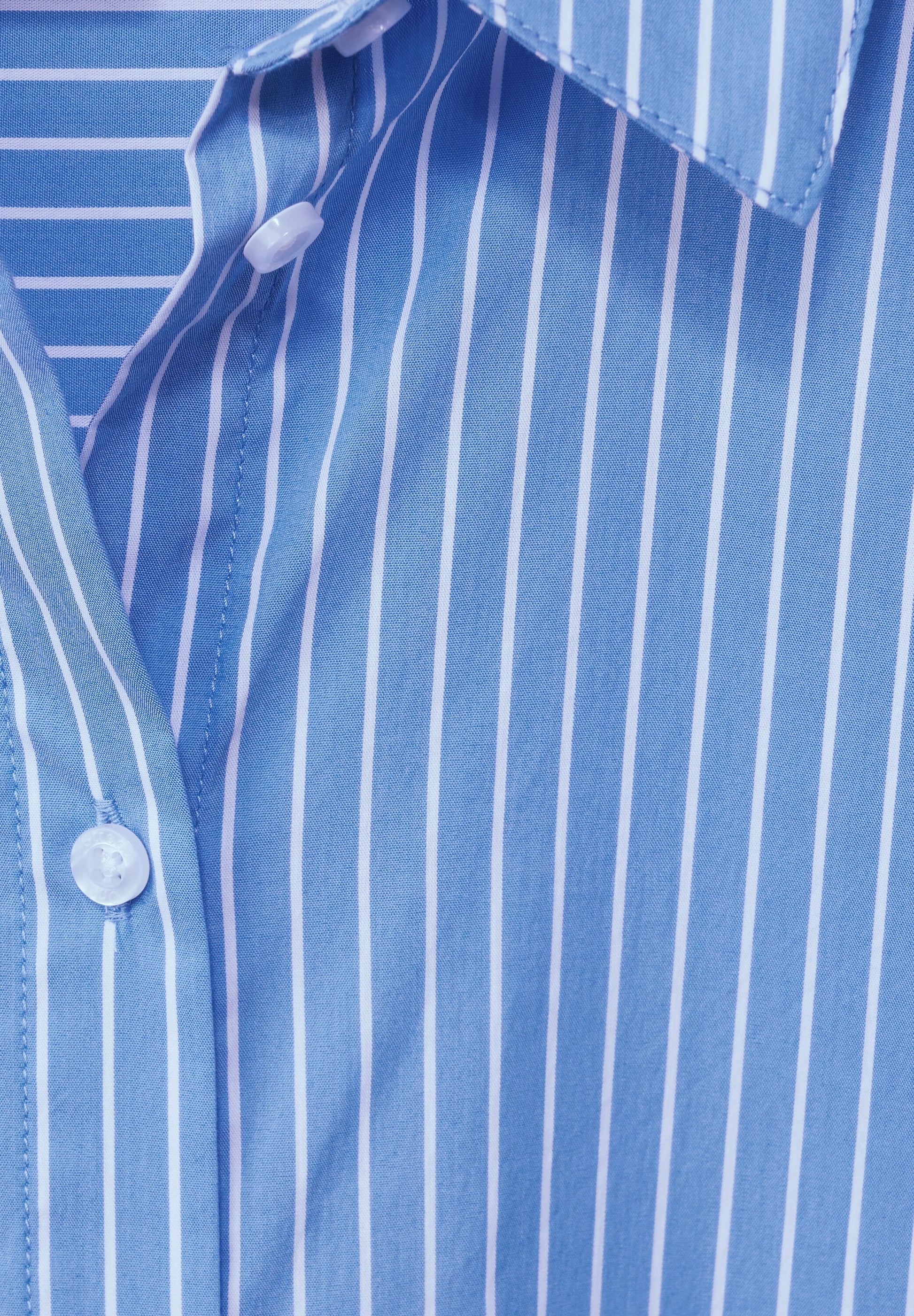Ein Detailfoto von einer Bluse mit Streifen und Knöpfen